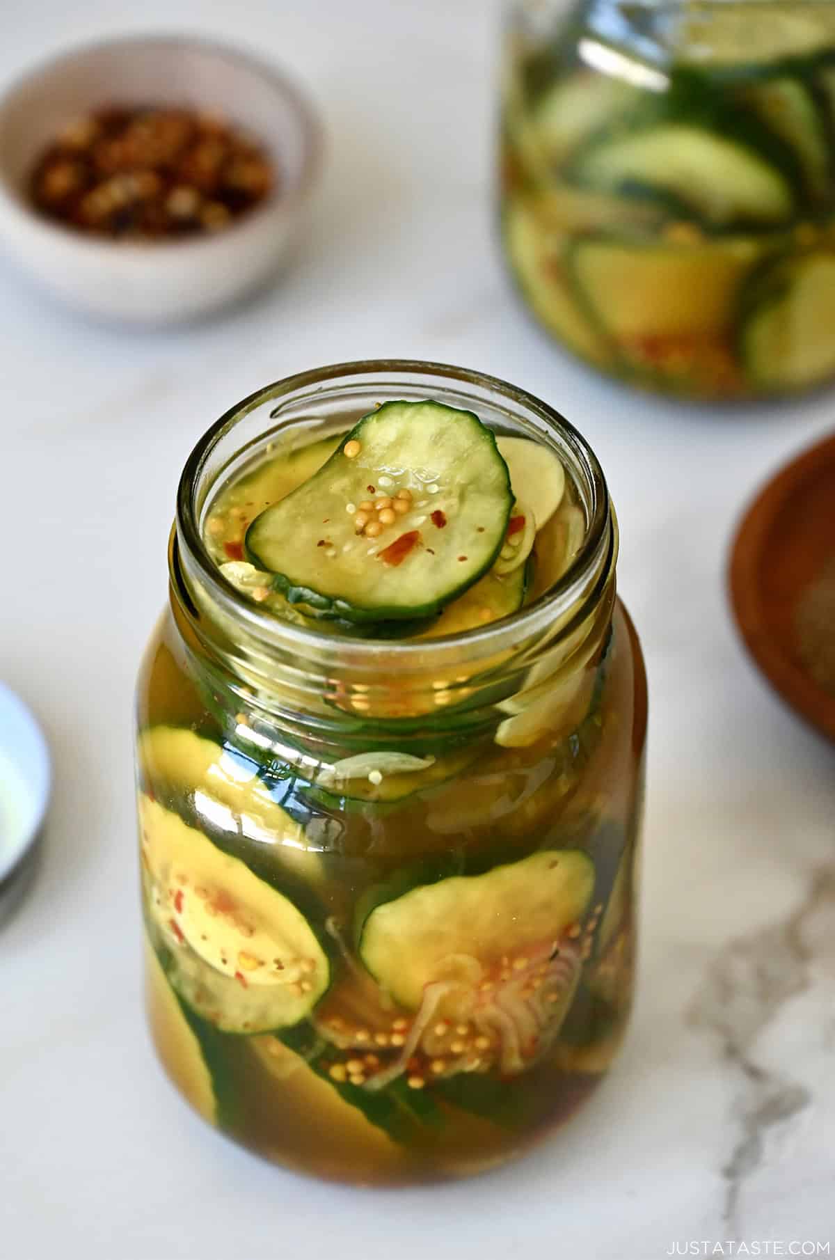 A glass pint jar filled to the brim with homemade bread and butter pickles.