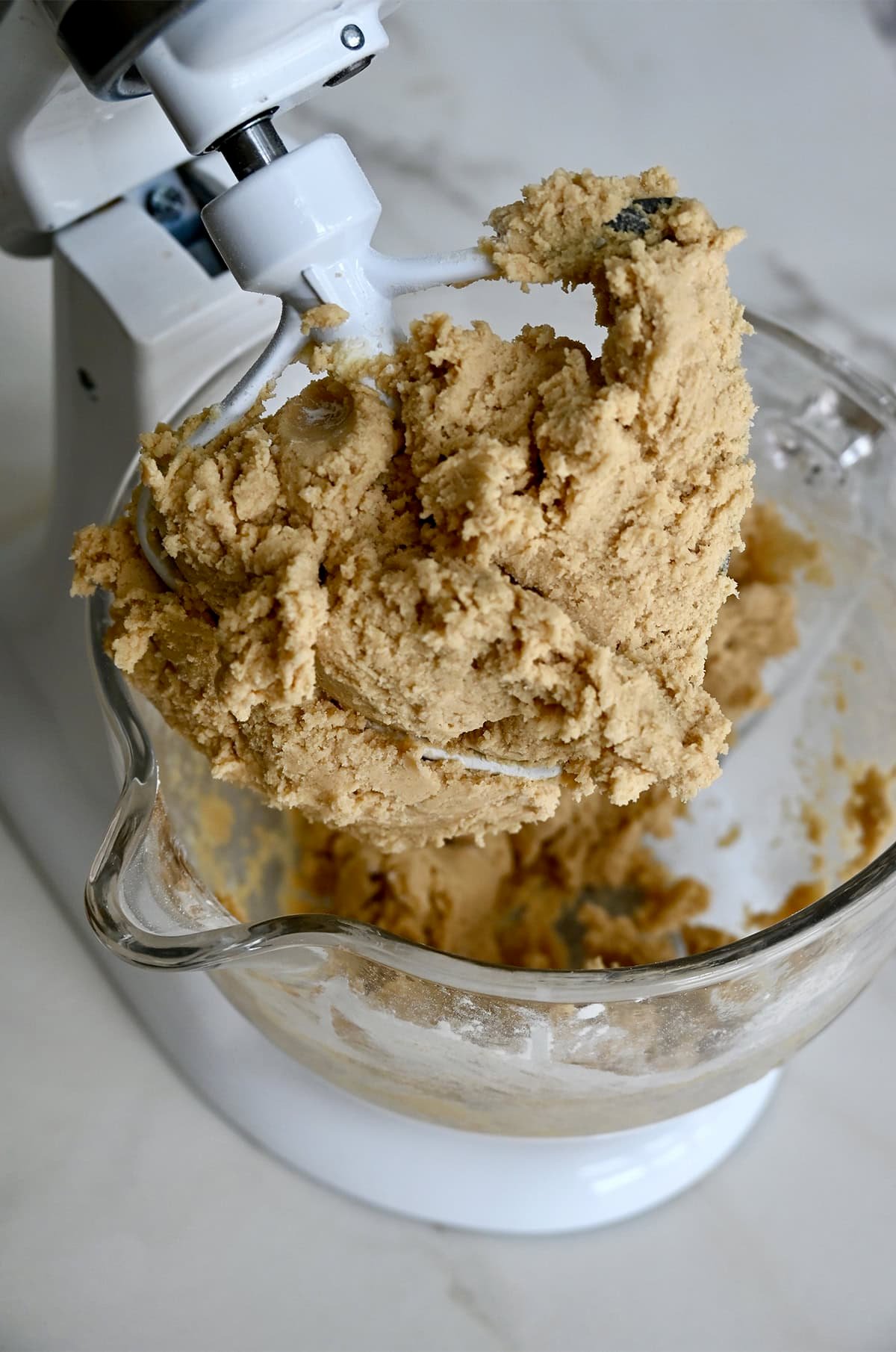 Chipless cookie dough covering the paddle attachment of a stand mixer.